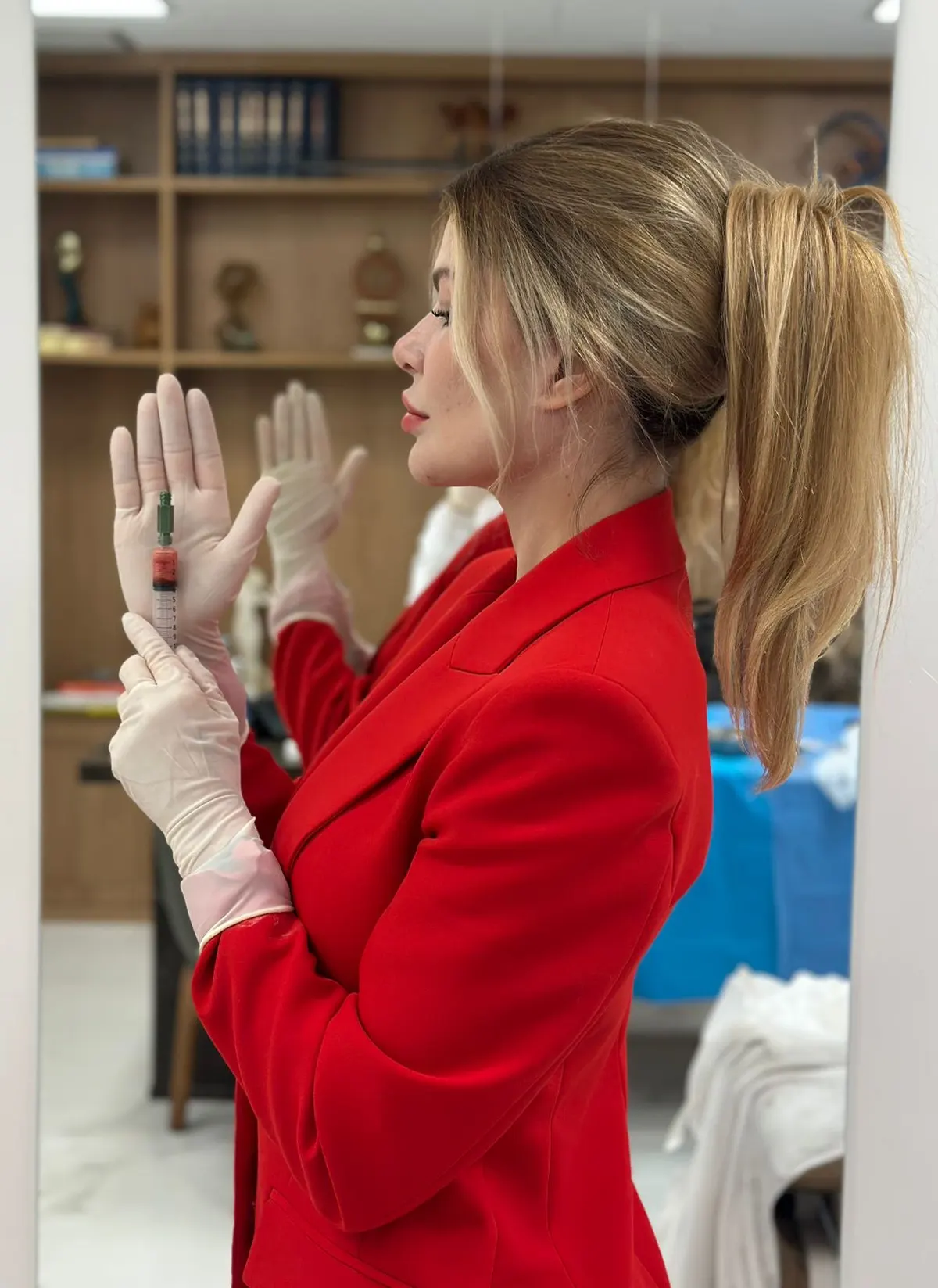 Dra. Priscila Buss de luvas, preparando material em ambiente clínico