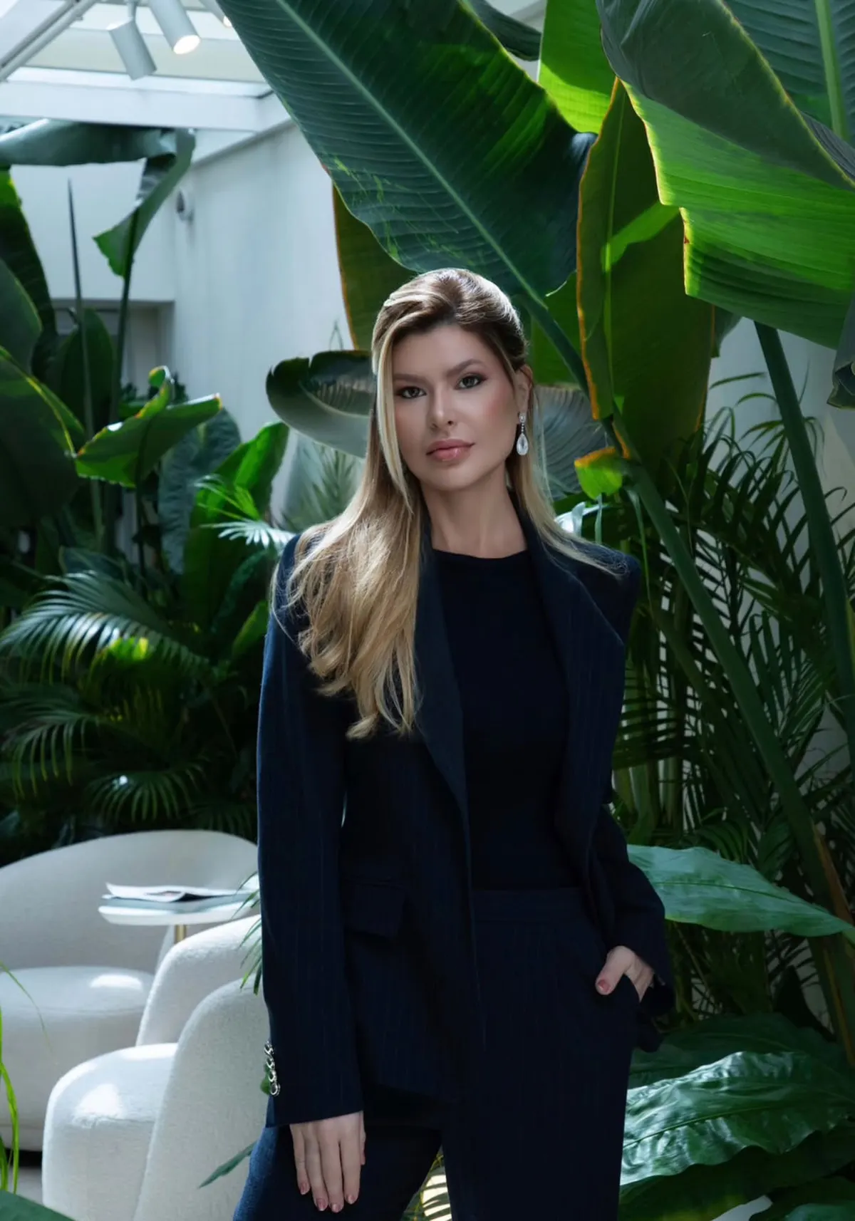 Retrato da Dra. Priscila Buss, de terno escuro, em ambiente com plantas